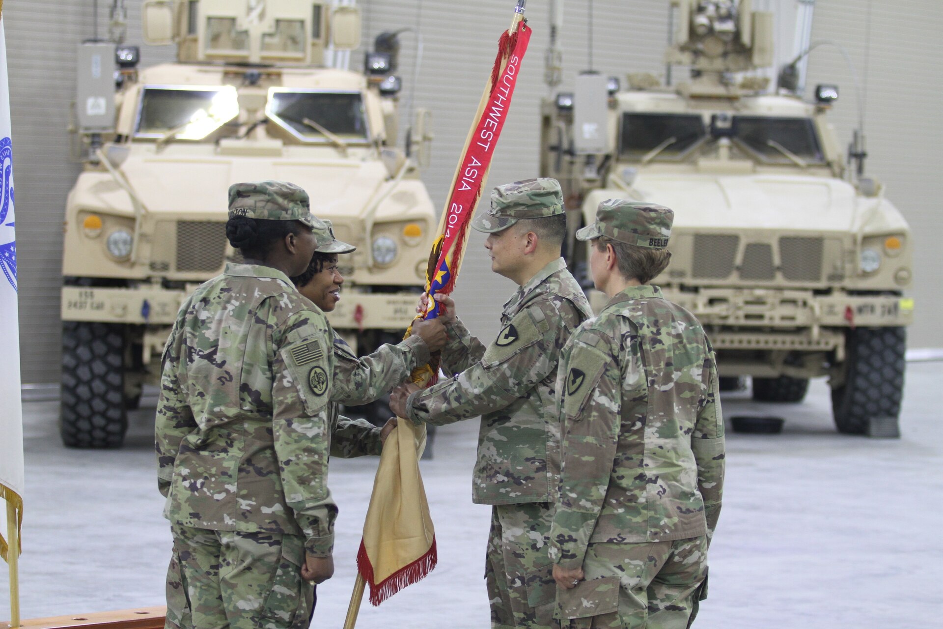 Colonel Ralph T. Borja, center, outgoing commander, 408th Contracting Support Brigade, accepts the unit colors from Command Sgt. Maj. DuJuania Deloatch, senior enlisted leader, 408th CSB, during a change of command ceremony at Camp Arifjan, Kuwait, June 27, 2019. Borja led the 408th CSB since June 2018 and ensured the successful awarding, management and support for more than $11 billion in contracts across the U.S. Army Central area of operations.