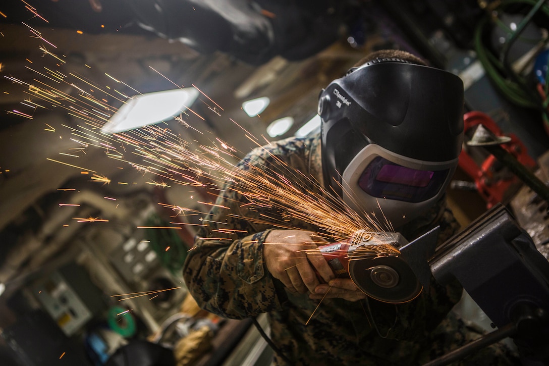 A Marine uses a tool to grind metal.