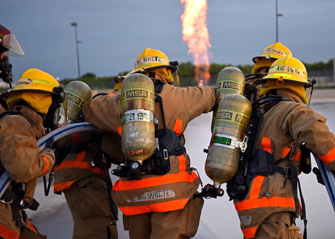 312th Training Squadron students work together to handle fire hoses that spray 115 pounds per square inch of pressure at the Louis F. Garland Department of Defense Fire Academy, June 27, 2019. All DoD firefighters were trained to work as a team just as they practiced at Goodfellow.  (U.S. Air Force photo by Airman 1st Class Ethan Sherwood)