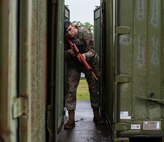 U.S. Air Force Airman Christopher Fuller, a 35th Security Forces Squadron entry controller, hides behind a shipping container during an agile combat employment exercise at Misawa Air Base, Japan, June 28, 2019. Fuller taught 35th Logistic Readiness Squadron how to move, shoot and communicate and applied their newly learned skills to realistic training scenarios, such as clearing buildings and shooting techniques during ACE. (U.S. Air Force photo by Staff Sgt. Brittany A. Chase)