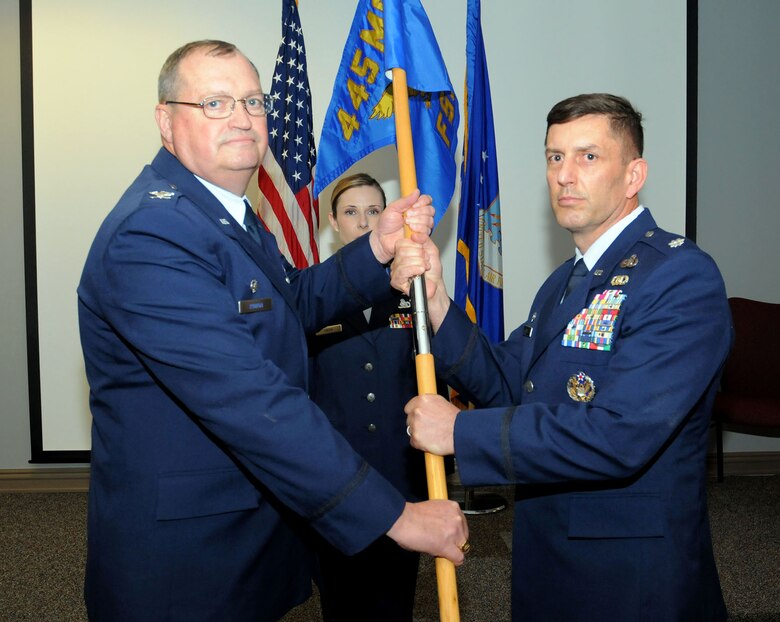 Col. Bryan Runion, 445th Mission Support Group commander, passes the guidon to Lt. Col. Darby Bess, incoming 445th Force Support Squadron commander, during an assumption of command ceremony June 2, 2019.