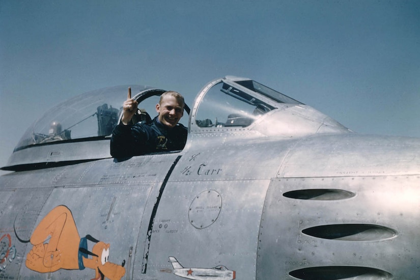 A man sits in an airplane cockpit smiling.