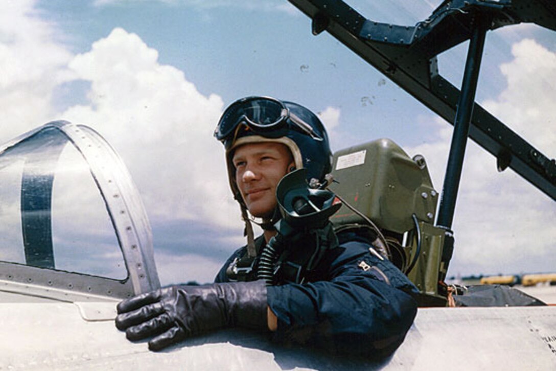 A man sits in an airplane cockpit smiling.