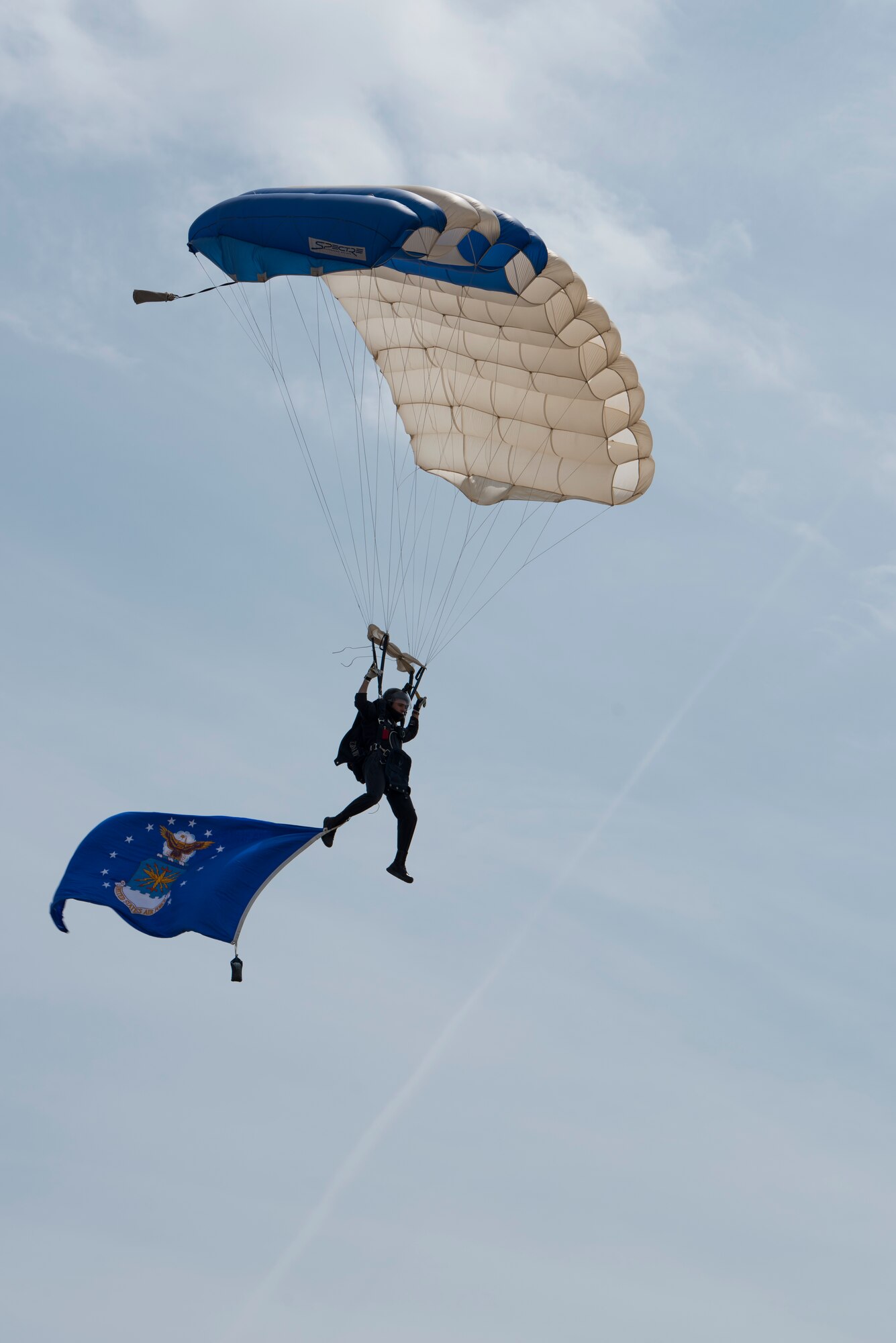 A U.S. Air Force Academy Wings of Blue parajumper glides in the flight line center stage while trailing the U.S. Air Force flag during the 2019 Skyfest Open House and Air Show at Fairchild Air Force Base, Washington, June 22, 2019. Skyfest 2019 offered a unique view of Team Fairchild’s role in enabling Rapid Global Mobility for the U.S. Air Force. The show featured more than 13 aerial acts and 16 static display aircraft, as well as other attractions and displays. (U.S. Air Force photo by Senior Airman Ryan Lackey)