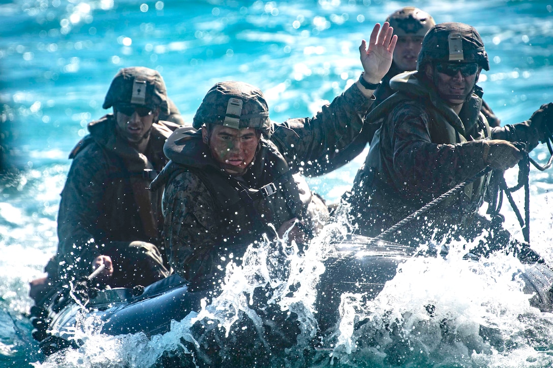 Marines prepare a safety line aboard a combat rubber raiding craft in the water.