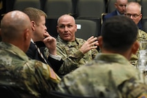 US soldiers talk with a man in a suit.
