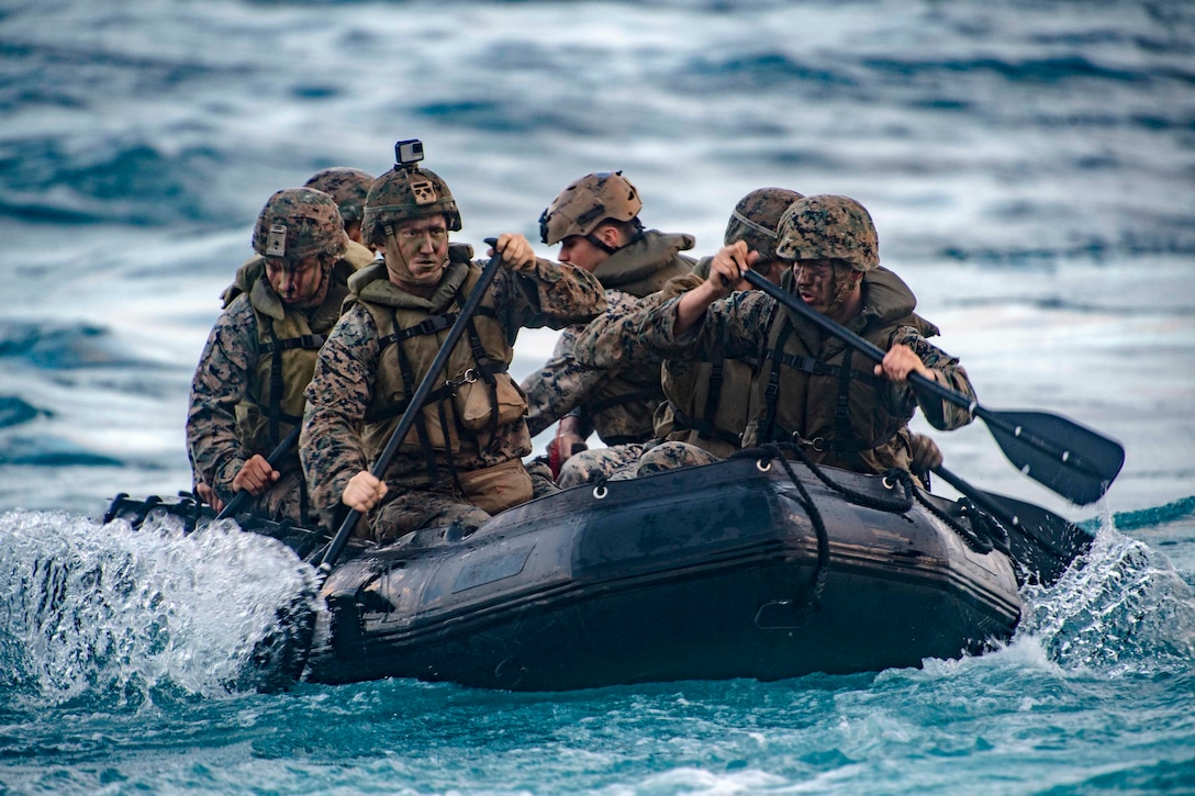 Marines ride in a small rubber boat.