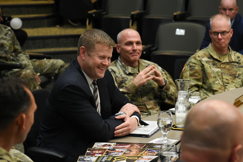 US soldiers with a man in a suit smiling.