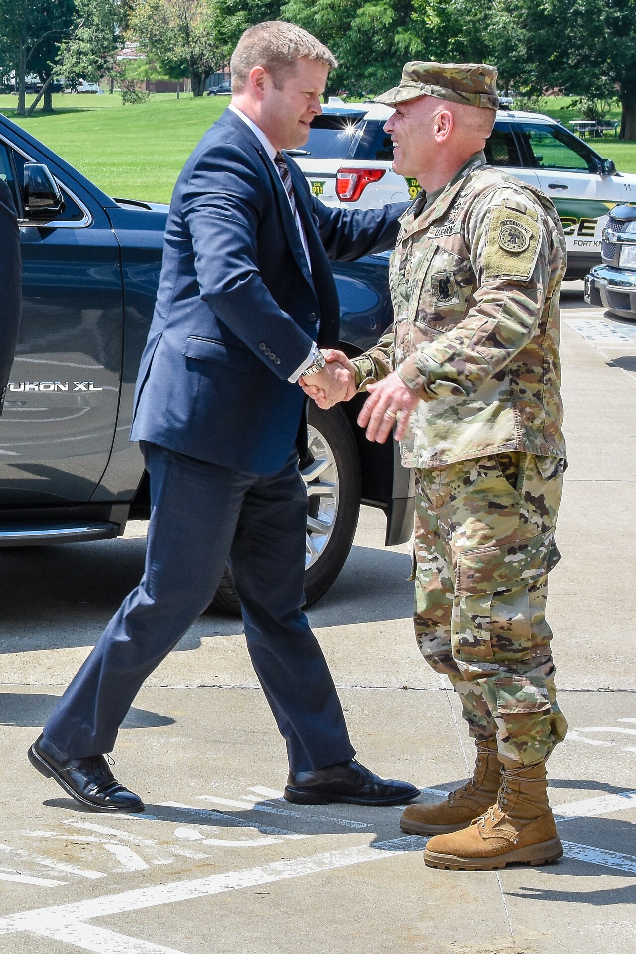 Army soldier shakes hands with a man in a suit.