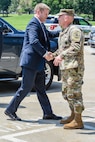 Army soldier shakes hands with a man in a suit.