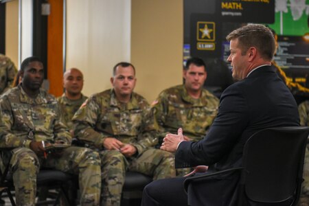 US Army soldiers speak with a man in a suit.