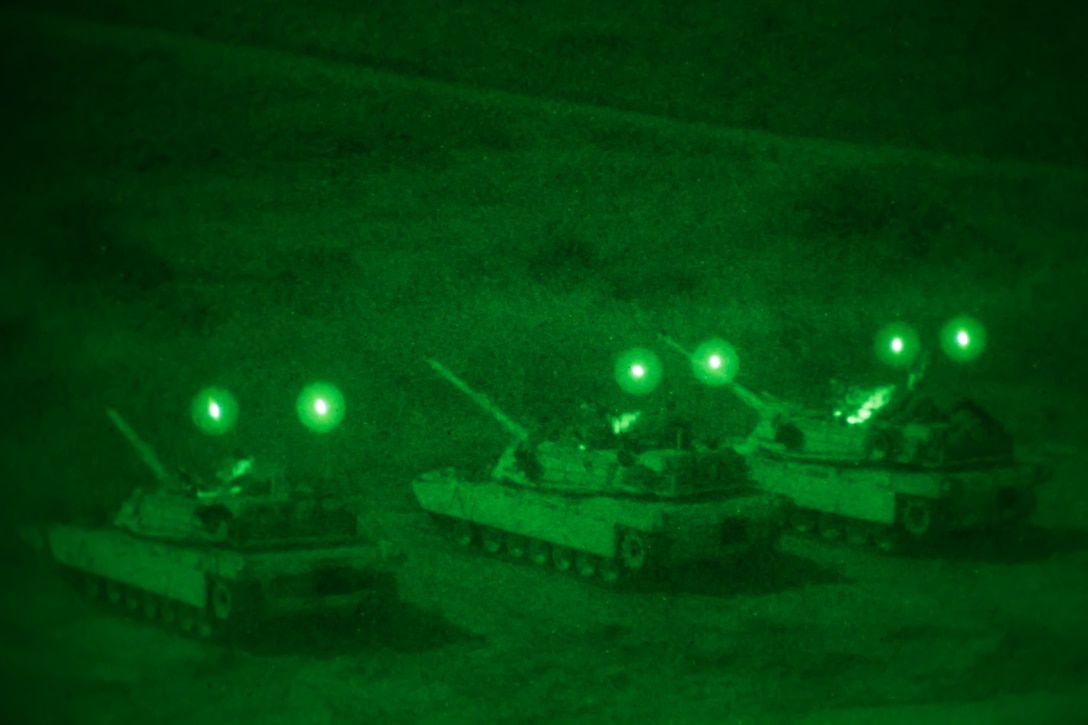 Three tanks are lined up side by side at night time.