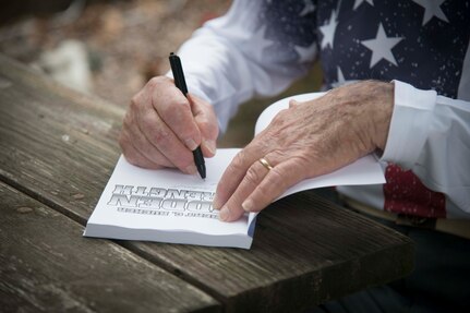 Robert C. Bueker, a local retiree and former World War II prisoner of war signs a copy of his life book, “Robert C. Bueker: Hidden Strength”, for First Lt. Christian Eberhardt, 502d Air Base Wing Public Affairs Officer  at his home July 3, 2019. Bueker celebrated his 95th birthday a day early with the help of Joint Base San Antonio presenting him with a personalized letter from Col. Mark Robinson, commander of the 12th Flying Training Wing, and a flag that has been flown onboard an F-16 during 2017 support operations in Afghanistan. (U.S. Air Force photo by: Airman 1st Class Shelby Pruitt)