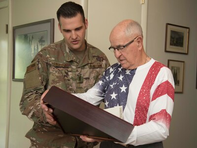 Robert C. Bueker, a local retiree and former World War II prisoner of war looks at flag that was given to him, with First Lt. Christian Eberhardt, 502d Air Base Wing Public Affairs Officer at his home July 3, 2019. Bueker celebrated his 95th birthday a day early with the help of Joint Base San Antonio presenting him with a personalized letter from Col. Mark Robinson, commander of the 12th Flying Training Wing, and a flag that has been flown onboard an F-16 during 2017 support operations in Afghanistan. (U.S. Air Force photo by: Airman 1st Class Shelby Pruitt)