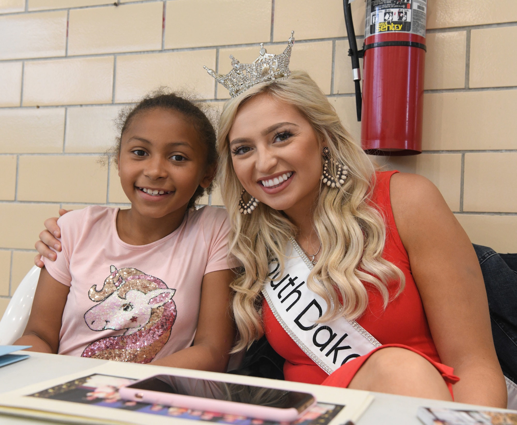 Amber Hulse, Miss South Dakota takes a photo with Angelisse Griffin during at the Summer Splash event at Ellsworth Air Force Base, S.D., July 1, 2019. Hulse came out to meet children on base, sign autographs and take photos with participants. (U.S. Air Force photo by Senior Airman Thomas Karol)