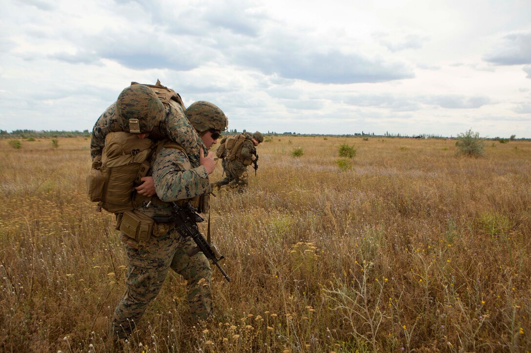 A sailor carries another sailor on his shoulders.