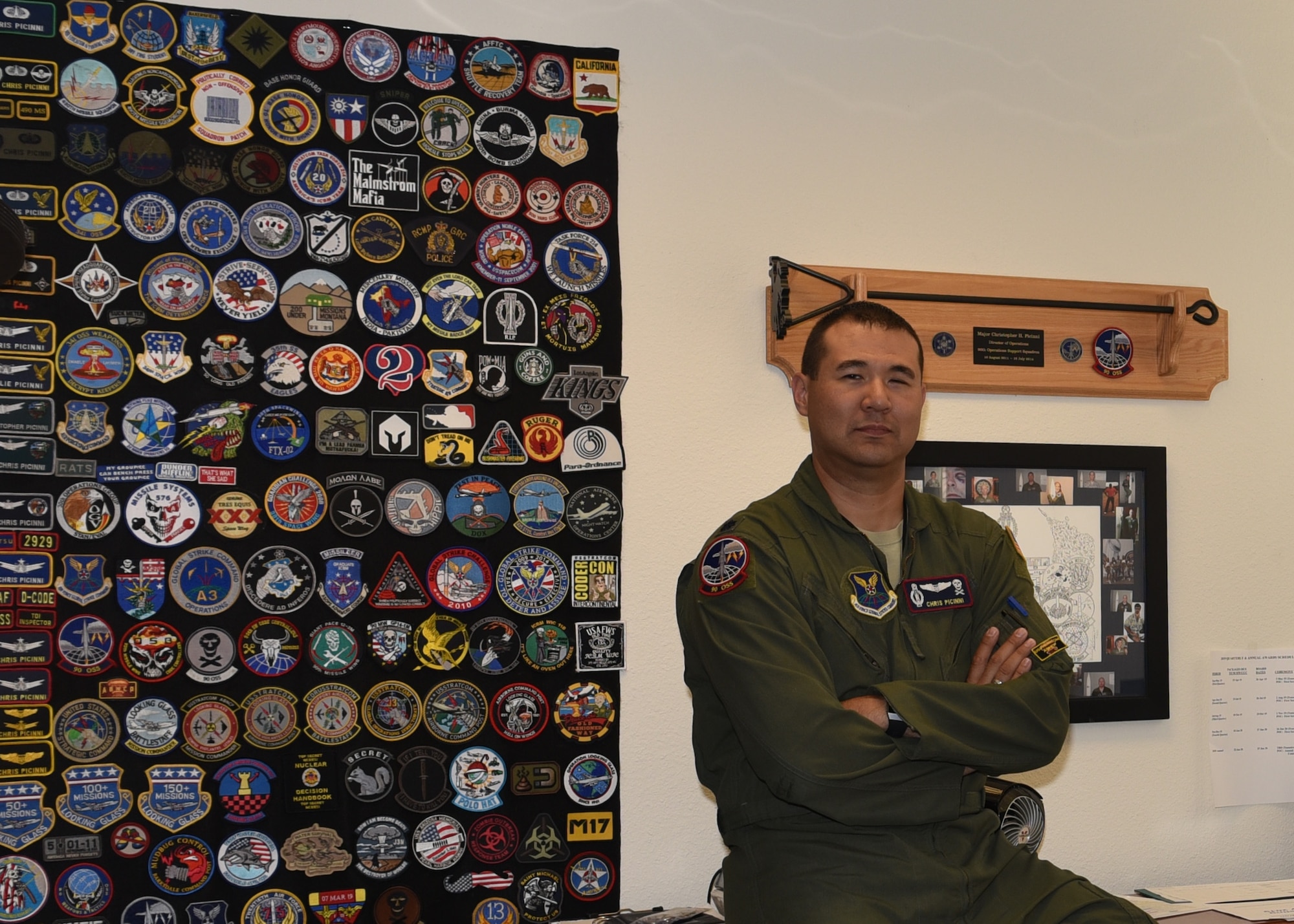 Lieutenant Colonel Christopher Picinni, 90th Operation Support Squadron director of operations, sits next to his patch wall with pride, July 2, 2019, on F.E. Warren Air Force Base Wyo. Picinni has collected a vast array of patches from various exercises, assigned units, and promotions. (U.S. Air Force photo by Senior Airman Braydon Williams)