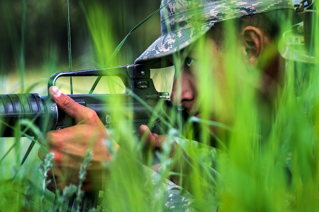An Air Force cadet takes cover in tall grass.