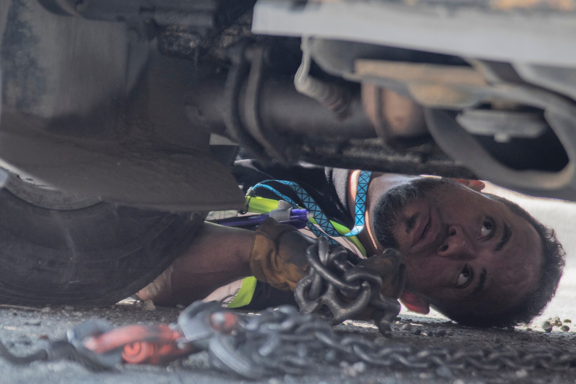 Edison Minyatty, an assistant tow truck operator with JT Towing LLC, attaches chains to a vehicle July 1, 2019, on Joint Base Elmendorf-Richardson, Alaska. Abandoned and illegally parked vehicles on Joint Base Elmendorf-Richardson, Alaska, are towed because they present safety hazards.