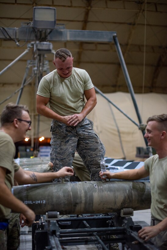 Airmen of 380th Expeditionary Maintenance Squadron socialize while building a GBU-38 June 21, 2019, at Al Dhafra Air Base, United Arab Emirates.