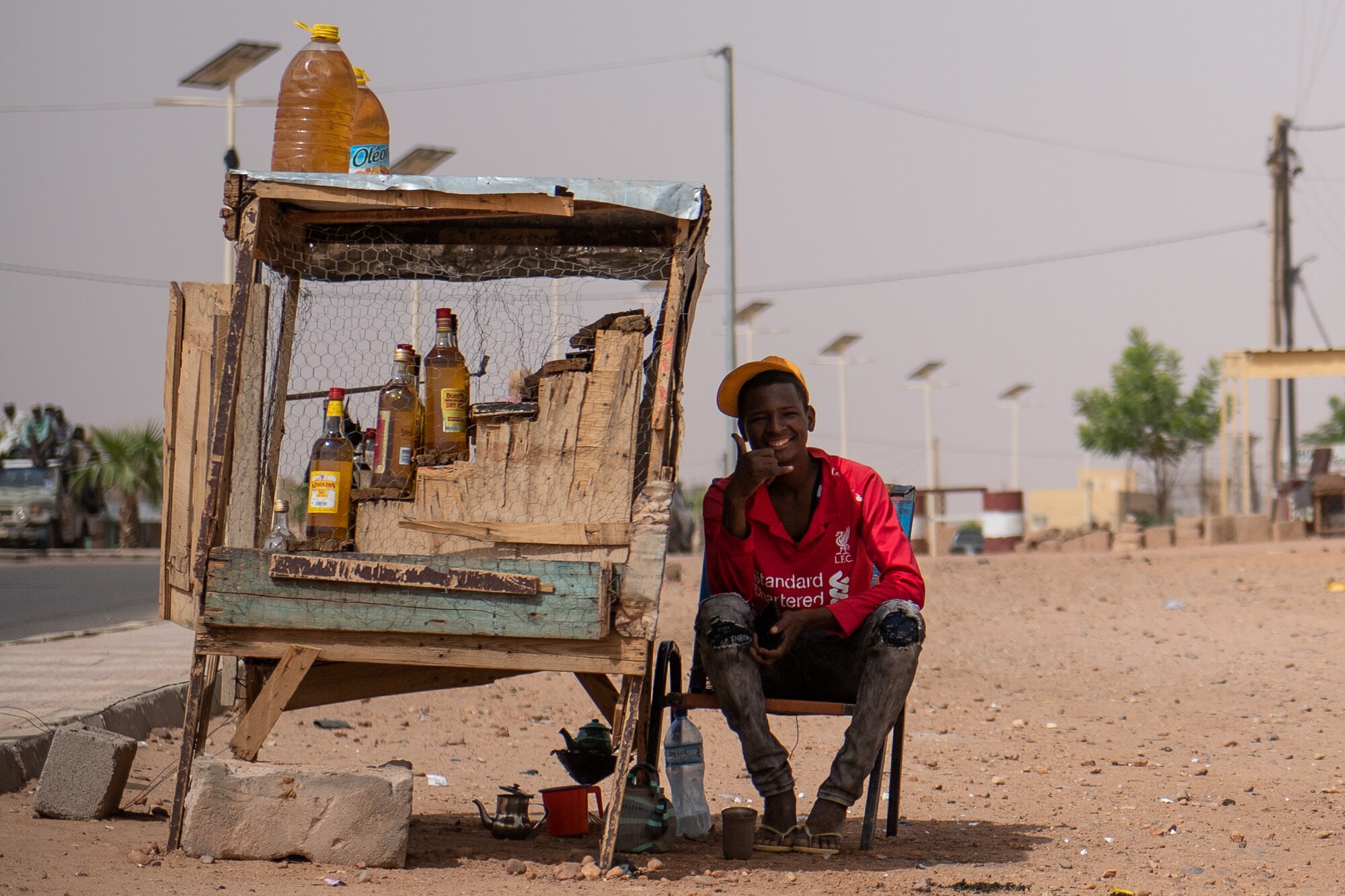 A Nigerien sits by a fuel stand in Agadez, Niger, June 27, 2019. Nigeriens use recycled juice containers and liquor bottles to sell fuel. The fuel stands can be spotted around the city by their wooden structure surrounded by metal wire. (U.S. Air Force photo by Staff Sgt. Devin Boyer)