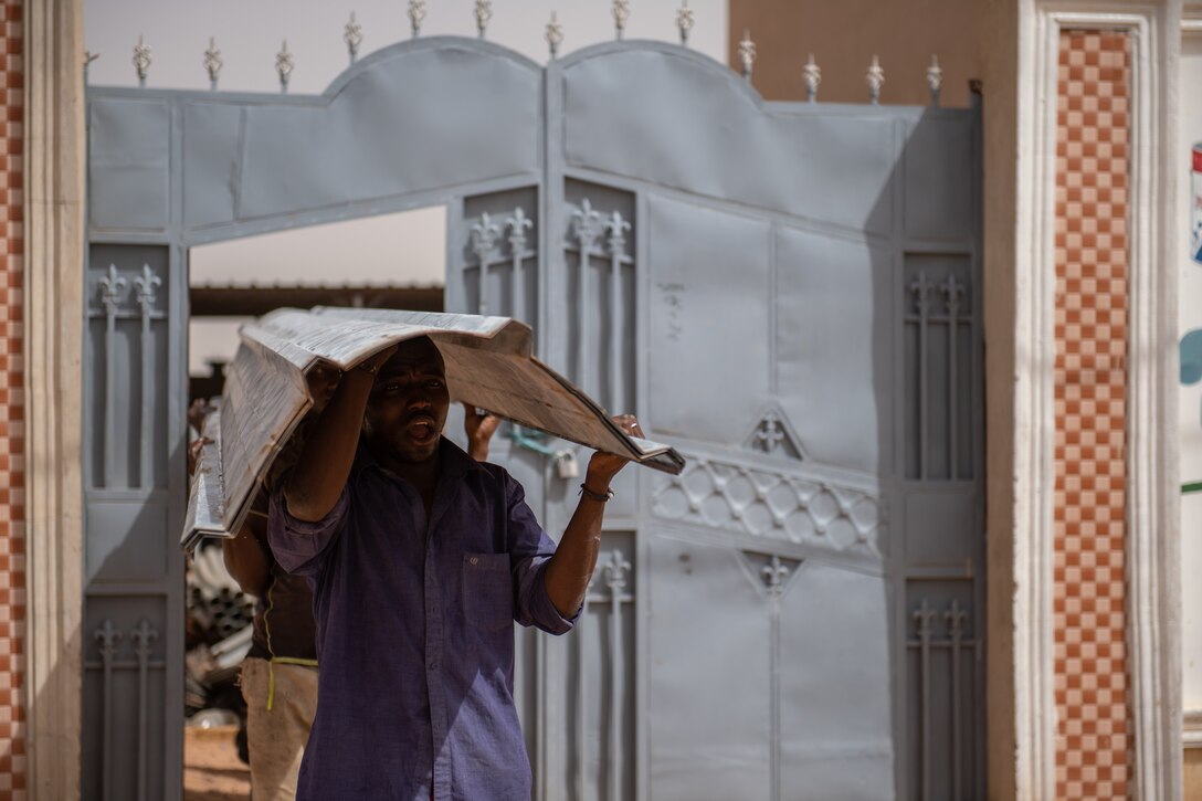 Nigerien employees from a local hardware store carry a sheet of tin roofing to a truck in Agadez, Niger, June 27, 2019. The 724th Expeditionary Air Base Squadron civil engineer flight installed the roofing on two classrooms in local villages. (U.S. Air Force photo by Staff Sgt. Devin Boyer)