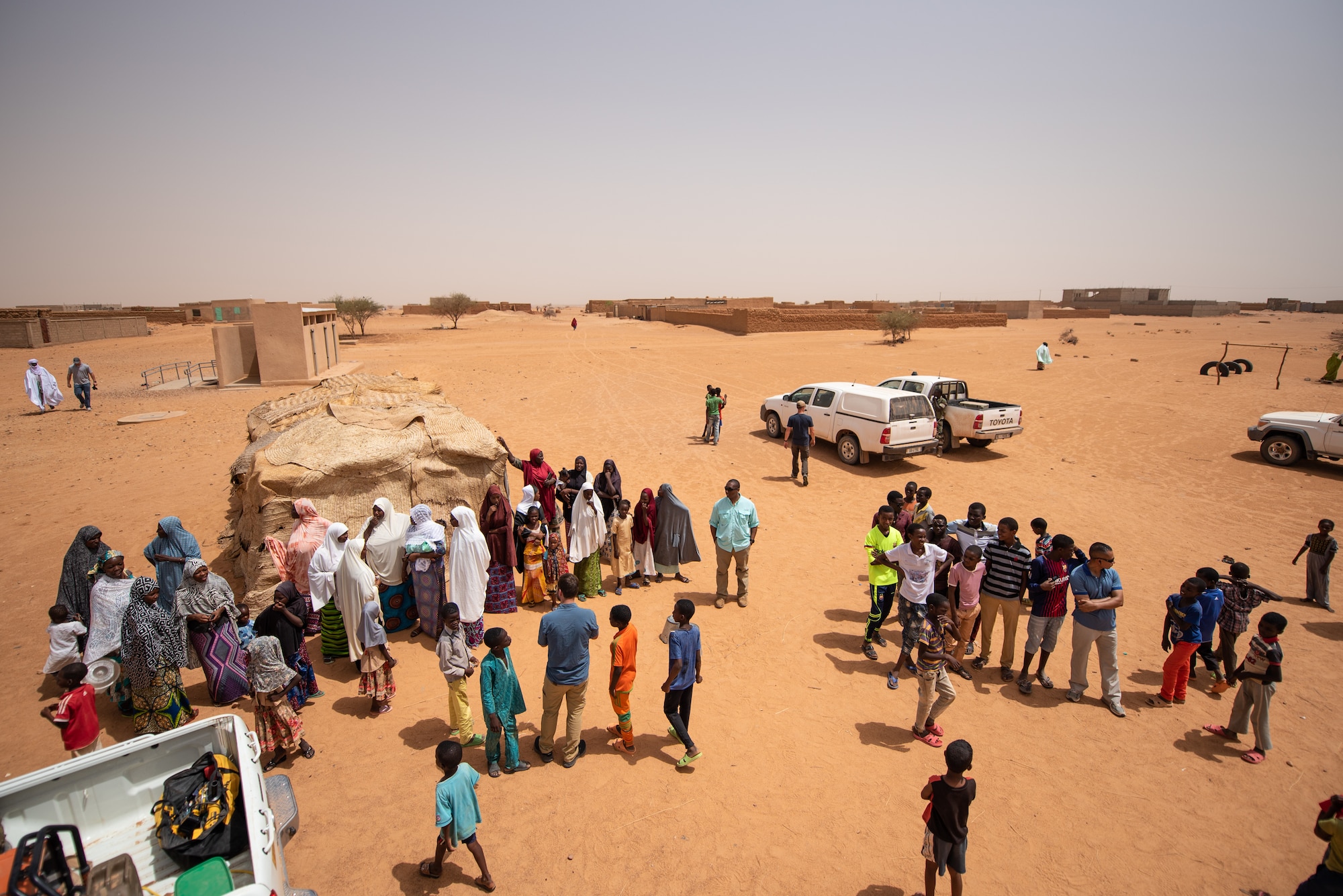 Nigeriens watch as Airmen assigned to the 724th Expeditionary Air Base Squadron civil engineer flight install tin roofing to a classroom at a village in Agadez, Niger, June 27, 2019. The Airmen from the civil engineer flight built the classroom and an additional one in another village. (U.S. Air Force photo by Staff Sgt. Devin Boyer)