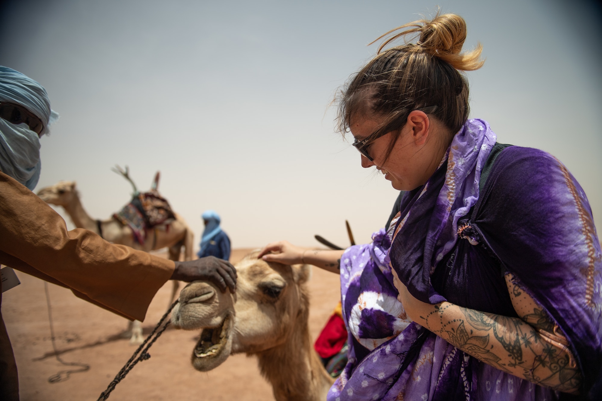 A U.S. service member assigned to Nigerien Air Base 201 pets a camel during a bazaar at the base in Agadez, Niger, June 30, 2019. The bazaar gave deployed members a chance to ride the camels and buy souvenirs to take home. (U.S. Air Force photo by Staff Sgt. Devin Boyer)