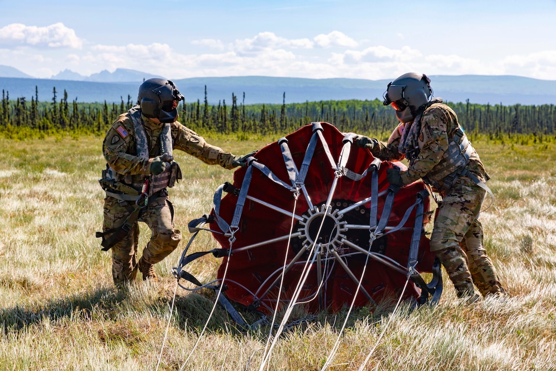 Two soldiers move a large piece of military equipment.
