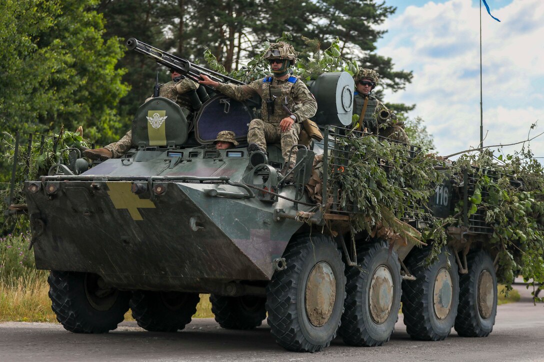 Soldiers ride in a tank.