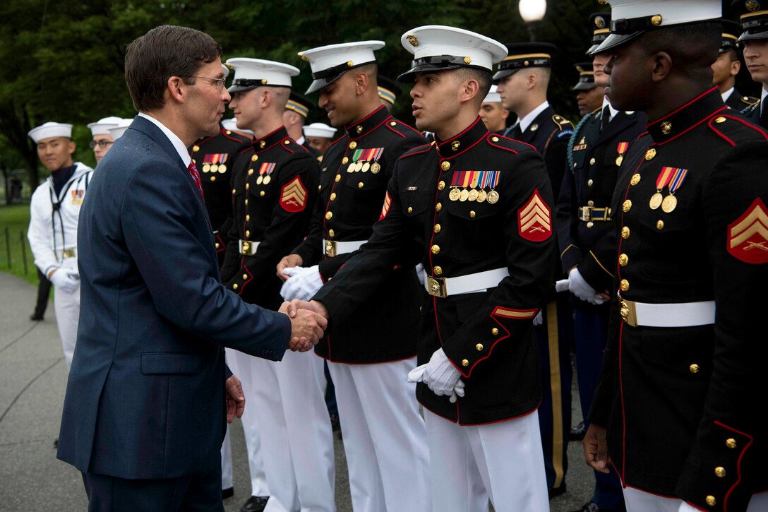 Acting Defense Secretary Dr. Mark T. Esper shakes hands with a Marine as fellow Marines and sailors look on outside.