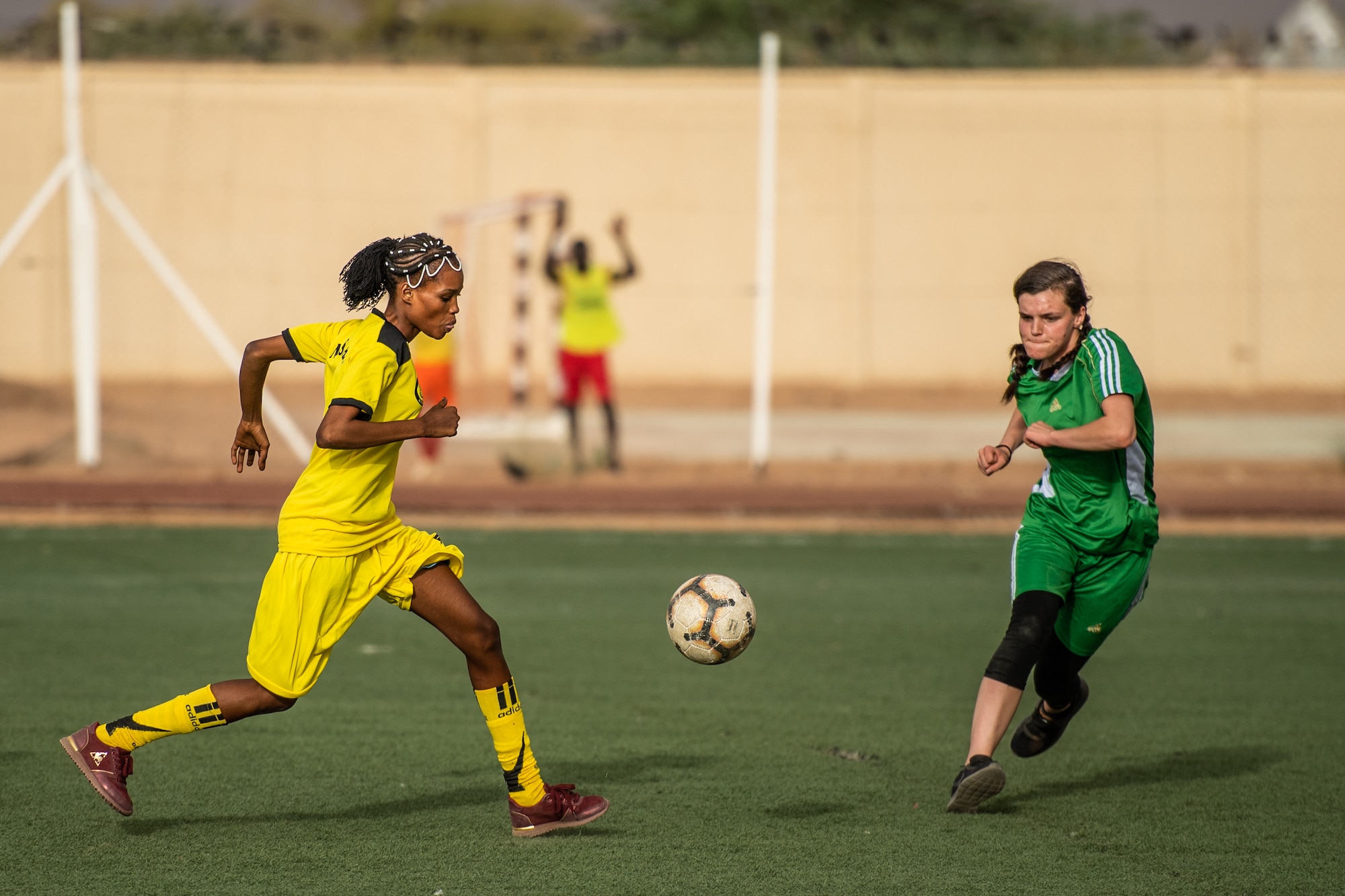 A player from the Nassara Athletic Club Women’s Soccer Team, and U.S. Air Force Airman 1st Class Hannah Stublar 31st Expeditionary Red Horse Squadron member, rush to the ball during a recreational game between Nigerien Air Base 201 and the Nassara Athletic Club Women’s Soccer Team at the Agadez Sports Stadium in Agadez, Niger, July 5, 2019. The civil affairs team held the game to build rapport and promote positive sentiment between the local community and AB 201 personnel. (U.S. Air Force photo by Staff Sgt. Devin Boyer)