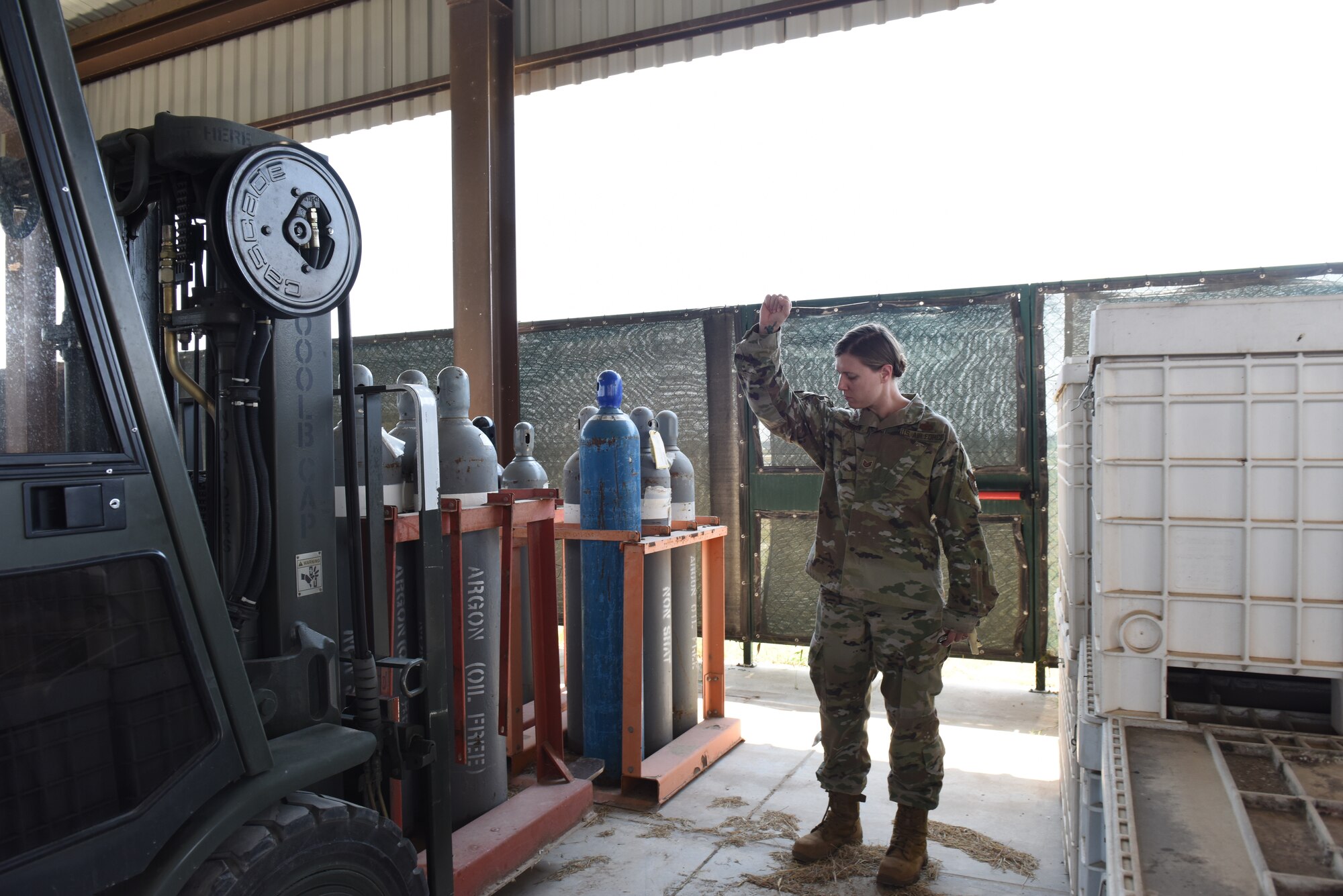 Photo of Tech. Sgt. Vanessa Acosta performing a spot for a forklift driver.