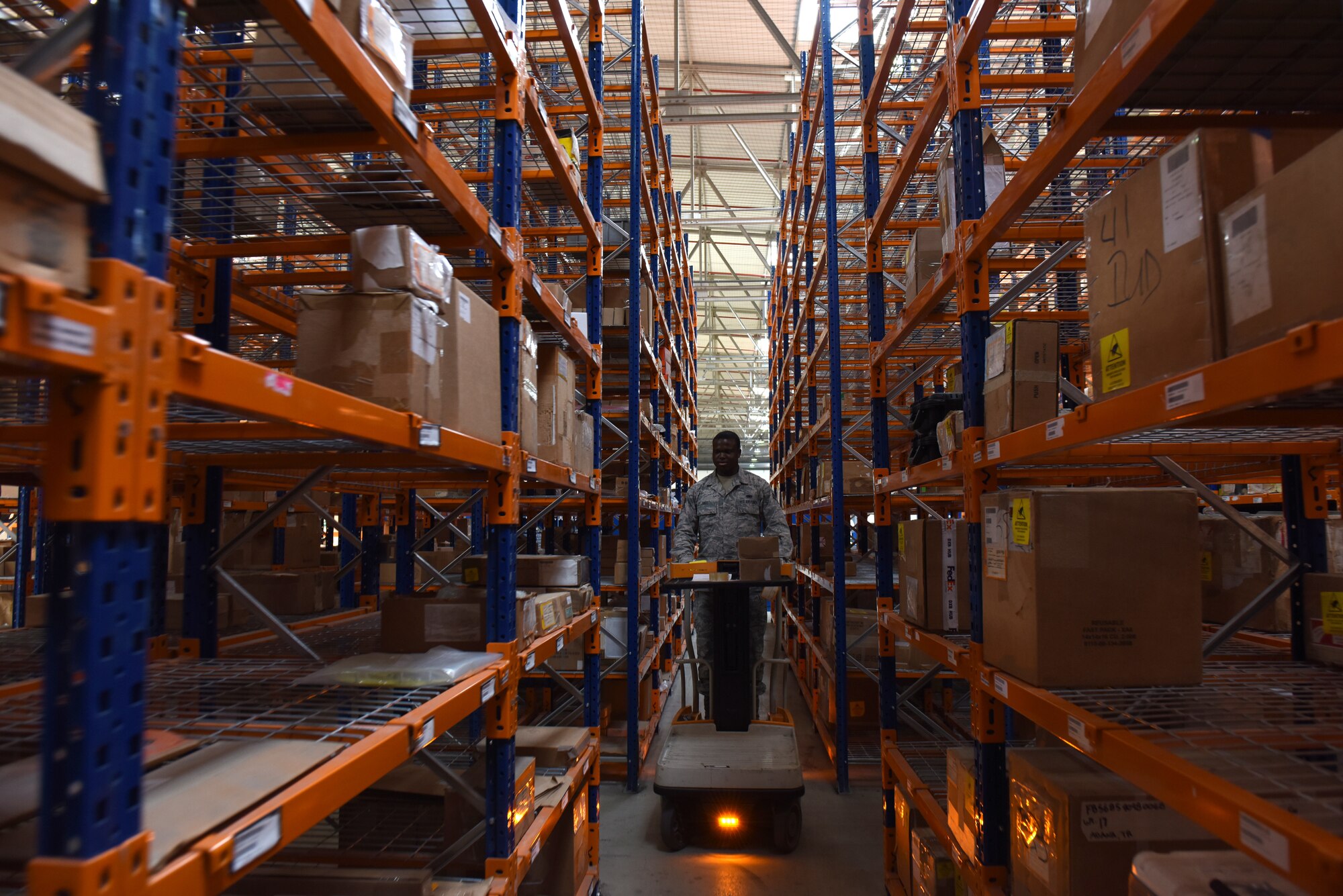 Photo of Senior Airman Joshua Hall operating a lift at a 39th Logistics Readiness Squadron warehouse.