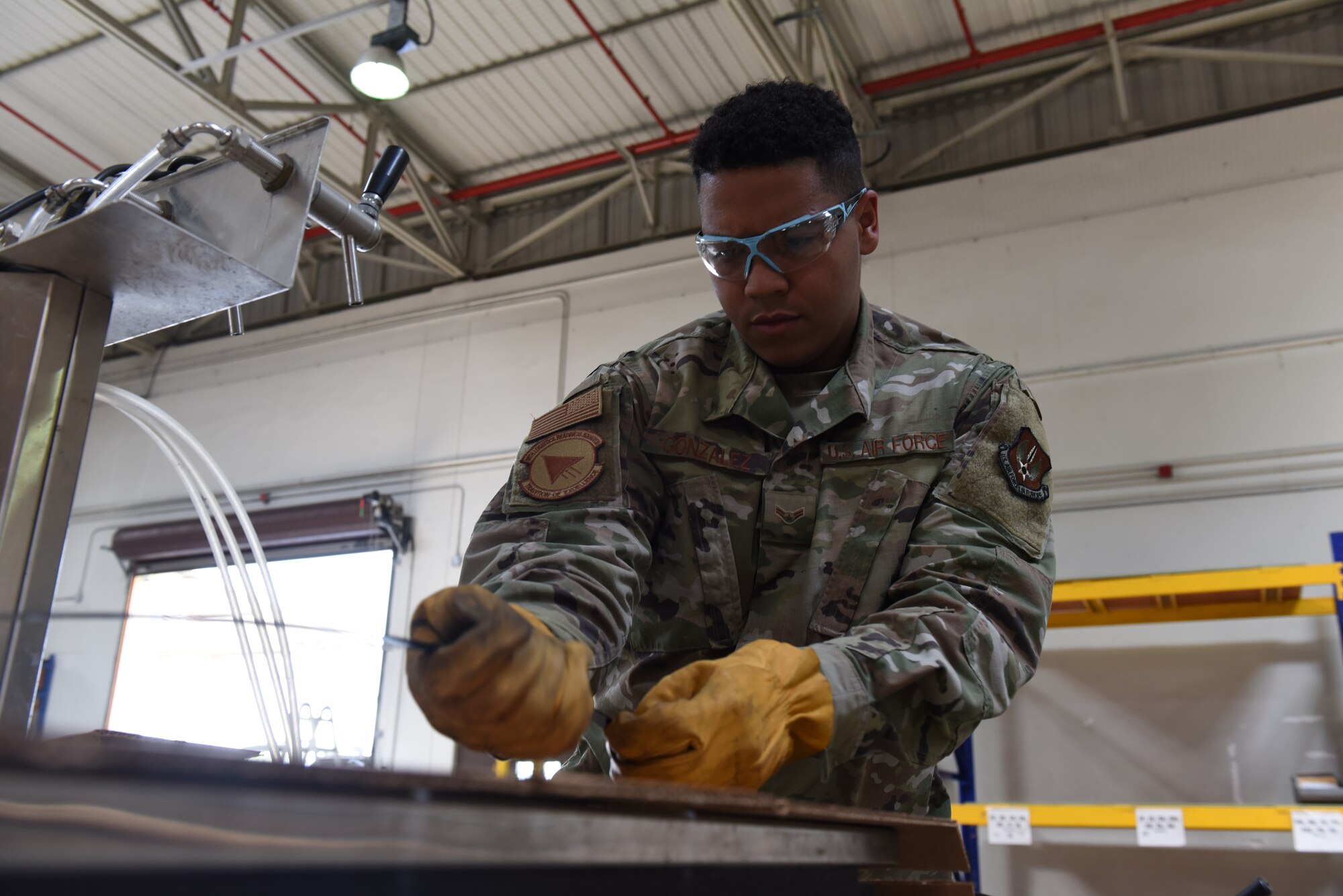 Photo of Senior Airman Sebastian Gonzalez tying down equipment to be shipped.