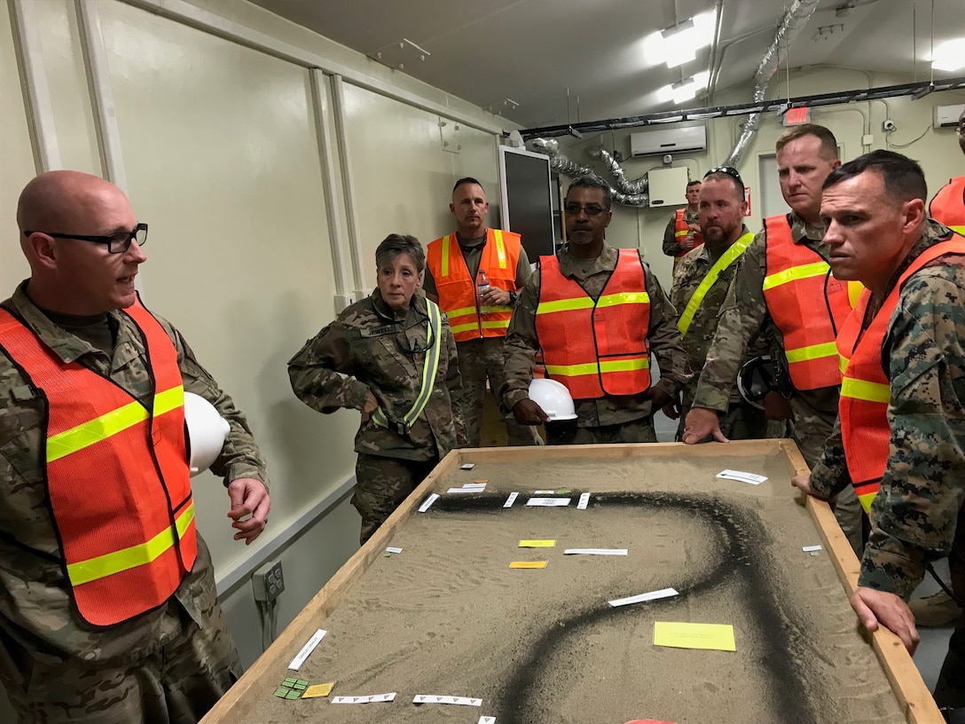 Navy Lt. Cmdr. Steven Harrell, officer-in-charge for DLA Disposition Services in Afghanistan, and Coleen Jewell, area manager, explain mobile expeditionary disposition capabilities and current planning efforts to Marine Brig. Gen. Brian Wolford, the new Bagram Airfield commander, and Army Col. David Raugh, the new Area Support Group-Afghanistan commander.  Pictured from left to right of  Harrell and Jewell are Craig Barrett, outgoing area manager; Jose Montanez, Bagram site chief, Rick Mann, property disposal specialist; Raugh and Wolford.