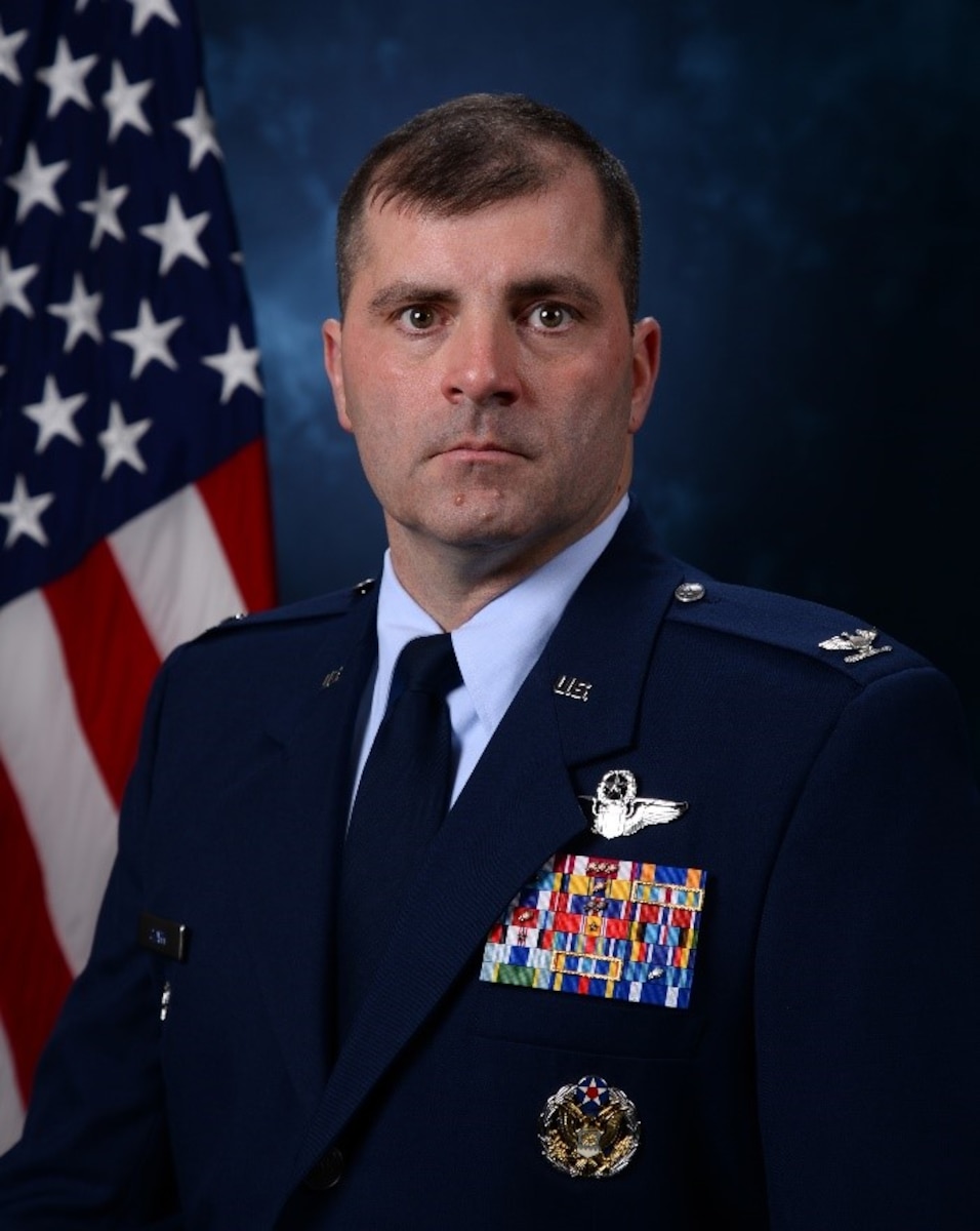 White male in Air Force Blues posing in front of American flag.