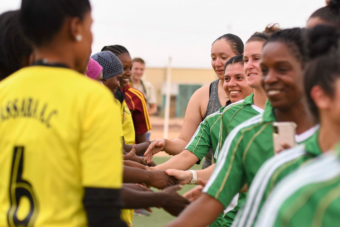 Two groups of women shake hands with each other.