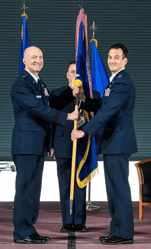 Air Force Test Center Commander Brig. Gen. Christopher Azzano, left, hands the AEDC guidon to Col. Jeffrey Geraghty charging him with command of AEDC during the Change of Command Ceremony June 18 in the Large Rocket Motor Test Facility J-6 at Arnold Air Force Base, Tennessee. (U.S. Air Force photo by Jill Pickett)