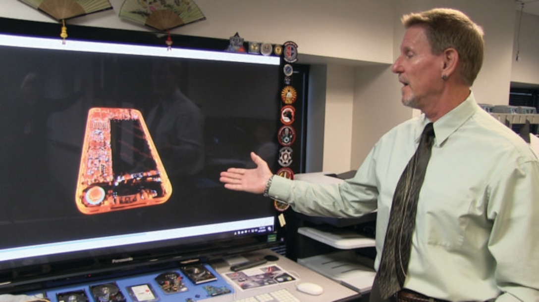 David Lutzow, chief of the Imaging and Extraction Section at the Defense Cyber Forensics Laboratory, points to a color X-ray image of a cellphone. The lab is among the many operations at the Department of Defense Cyber Crime Center (DC3) in Linthicum, Md. (Photo by Bryan Spann/ Ft. Meade/PA)