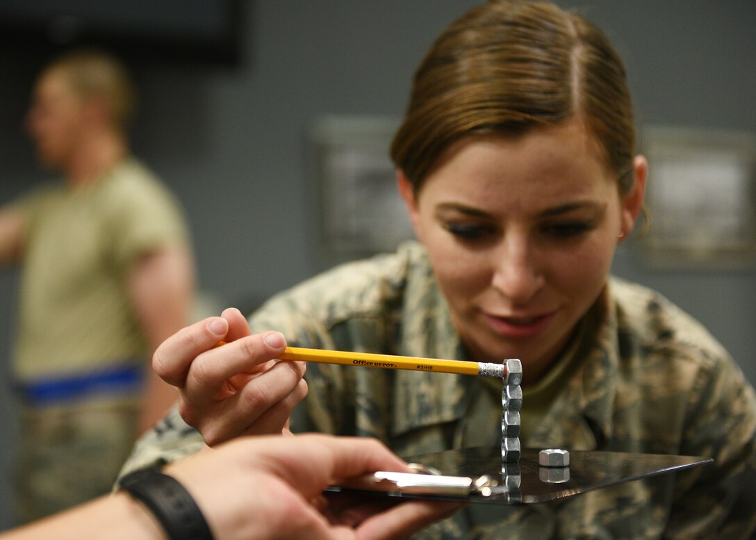 Participants of the Mental Fitness Obstacle Course attempt to perform tasks involving fine motor skills after completing rounds of physical activity at the event center on Goodfellow Air Force Base, Texas, July 2, 2019. The course is part of a broader learning initiative designed by the 17th Training Group to indoctrinate new technical training students into an active learning environment. (U.S. Air Force photo by Staff Sgt. Chad Warren/Released)