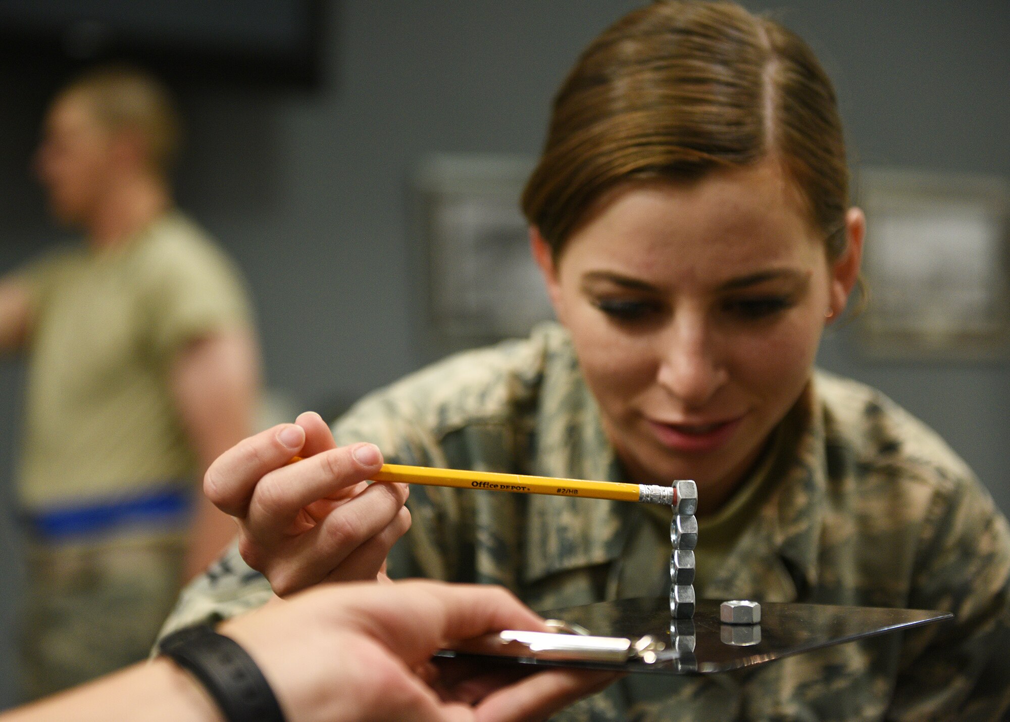 Participants of the Mental Fitness Obstacle Course attempt to perform tasks involving fine motor skills after completing rounds of physical activity at the event center on Goodfellow Air Force Base, Texas, July 2, 2019. The course is part of a broader learning initiative designed by the 17th Training Group to indoctrinate new technical training students into an active learning environment. (U.S. Air Force photo by Staff Sgt. Chad Warren/Released)