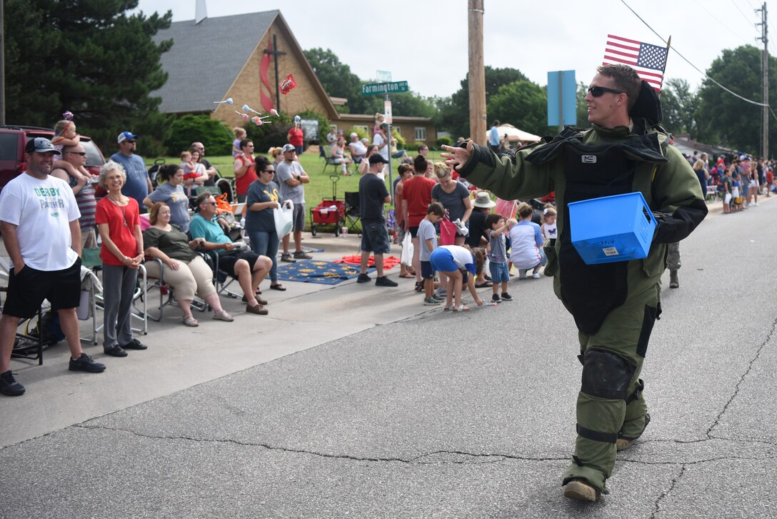 Staff Sgt. Zachary Logan, 22nd Civil Engineer Squadron explosive ordnance disposal team leader, throws candy to spectators watching the parade July 4, 2019, in Derby, Kan. EOD drove their work vehicle in the parade and wore a bomb suit, which is used while defusing unexploded ordnances. (U.S. Air Force photo by Airman 1st Class Alexi Myrick)