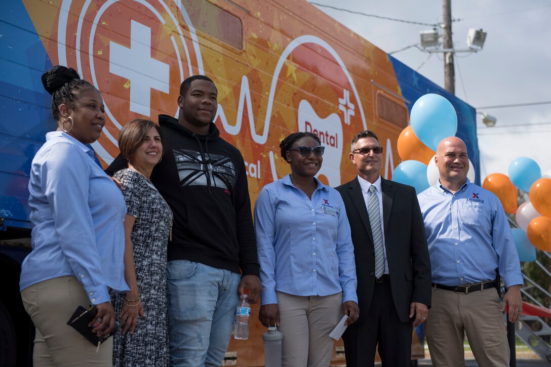 National Football League player Daron Payne takes a photo with Army and Air Force Exchange Services employees during the grand opening of the Dentrust Optimized Care Solutions mobile treatment facility at Joint Base Langley-Eustis, Virginia, July 8, 2019.
