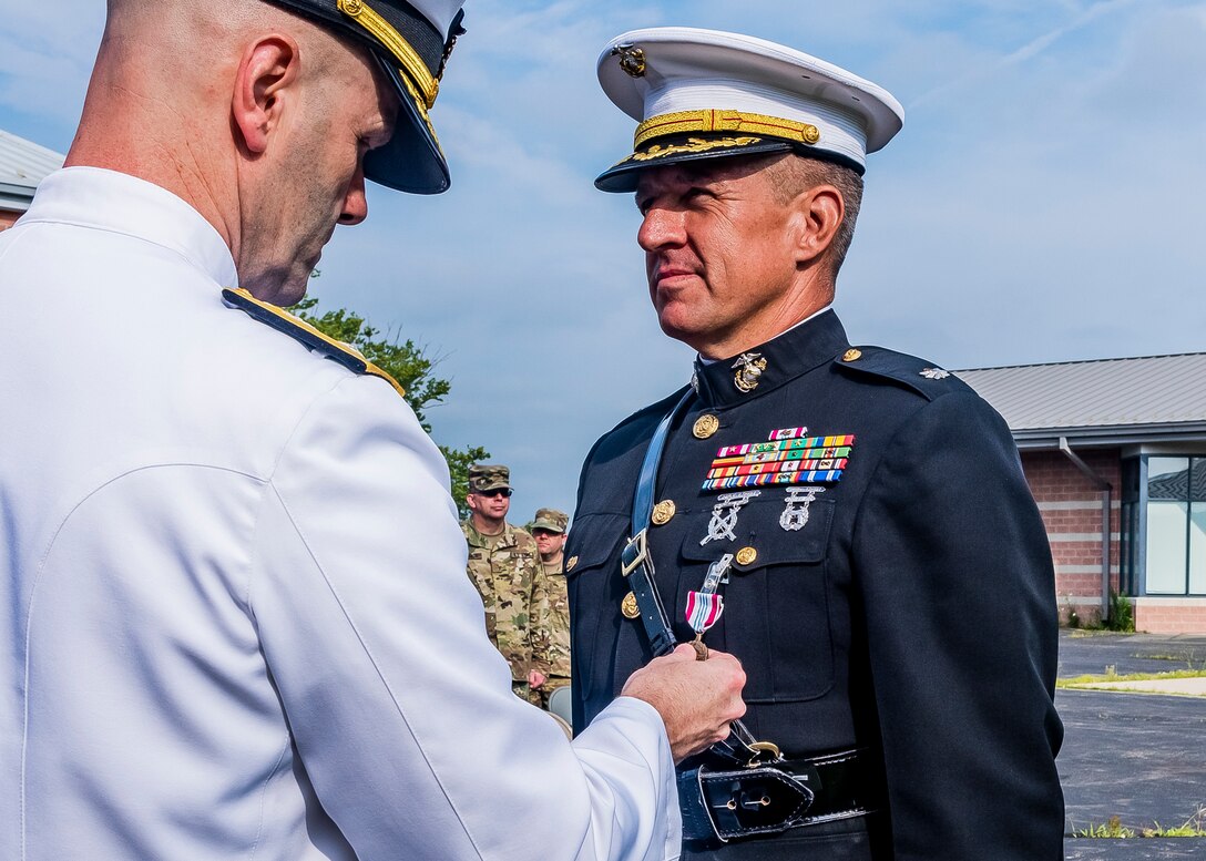 Navy Admiral awarding a medal to Marine Corps Lt. Col. During a retirement ceremony.