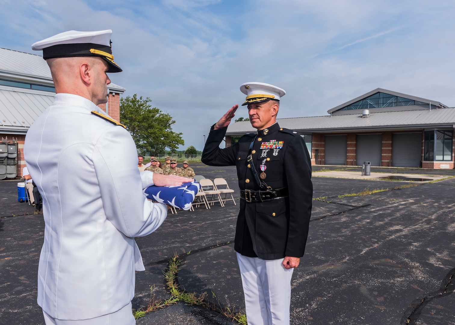 Navy rear admiral lower half presenting a United States Flag to a Marine Corps lieutenant colonel during a retirement ceremony.