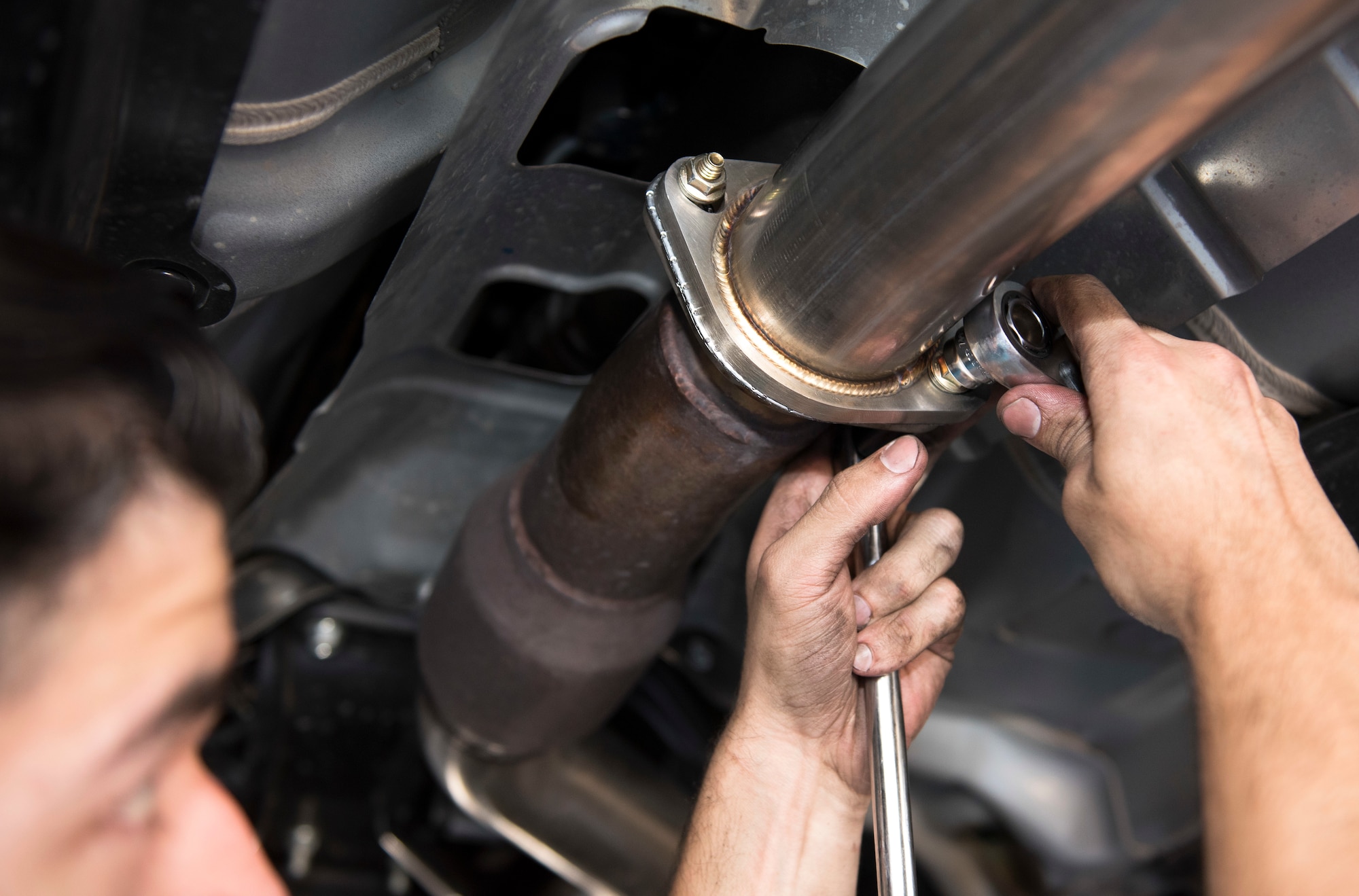 Senior Airman Igor Pacheco, 56th Medical Support Squadron lab technician, uses a ratchet to loosen a bolt on an exhaust system’s middle piping June 29, 2019, at the Auto Hobby Shop at Luke Air Force Base, Ariz.