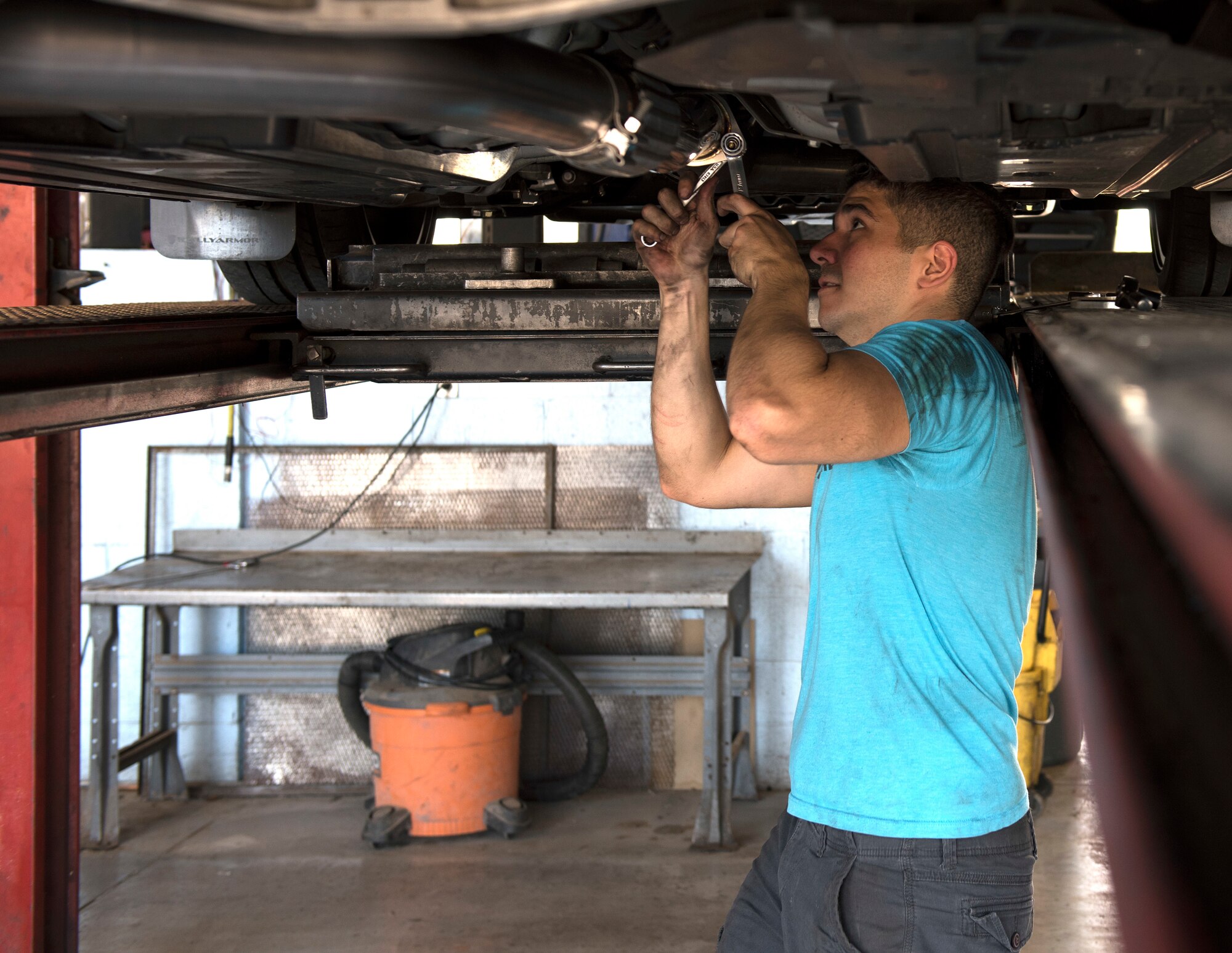 Senior Airman Igor Pacheco, 56th Medical Support Squadron lab technician, uses a ratchet and wrench to tighten a clamp on the middle piping while replacing an exhaust system on his vehicle June 29, 2019, in the Auto Hobby Shop at Luke Air Force Base, Ariz.
