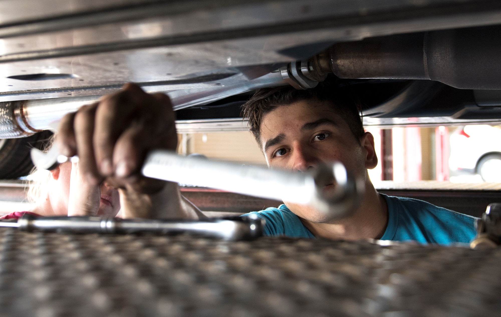 Senior Airman Igor Pacheco, 56th Medical Support Squadron lab technician, reaches for a wrench while replacing an exhaust system on his vehicle June 29, 2019, in the Auto Hobby Shop at Luke Air Force Base, Ariz.