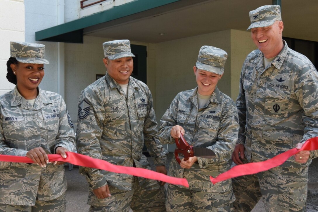 Col. Michael Hough, 30th Space Wing commander, holds a ribbon as Airman 1st Class Aubree Milks, 30th Space Wing Public Affairs photojournalist, cuts the ribbon during the grand opening of a new room within the dormitories August 23, 2018, at Vandenberg Air Force Base, Calif. Since one of Hough’s main priorities is to take care of the Airmen, he allowed Airmen to renovate a room within their living quarters to better their quality of life. (U.S. Air Force photo by Airman 1st Class Hanah Abercrombie)